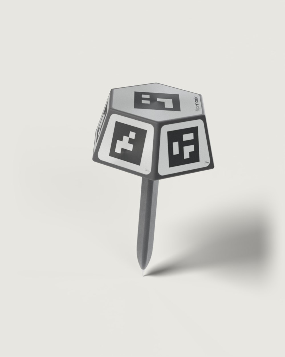 Tipmark PEN-10 standing on its steel point, leaning a little: a black hexagonal head with a metal code plate in every face, six stainless screws under the lid, on a slim black anodised shaft